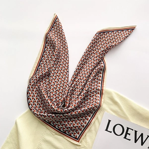 Macro shot of square silk scarf with geometric triangle patterns on yellow knitwear