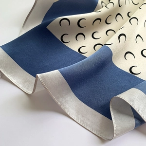 Close-up of silk scarf fabric showing elegant crescent moon pattern and smooth texture