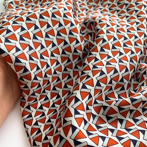 Detail of silk scarf showing orange and blue geometric patterns and soft texture