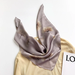 Gray-purple silk scarf with ginkgo leaf print draped on a yellow shirt top view
