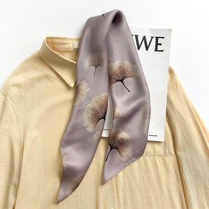 Close-up of a premium silk scarf with elegant ginkgo leaf pattern on yellow shirt