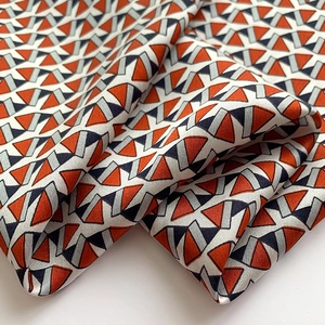 Macro shot of silk scarf fabric showing orange and navy geometric patterns and texture