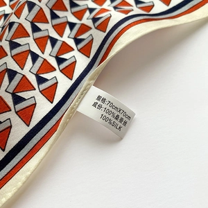 Close-up of 100% mulberry silk scarf with geometric orange and navy blue patterns