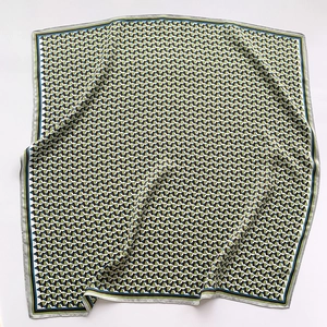 Detailed flat lay of geometric triangle pattern silk scarf with green and black borders