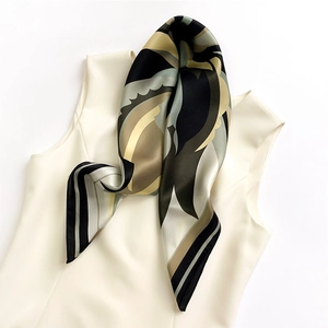 Dettaglio di un foulard di seta a motivi geometrici drappeggiato su un top beige