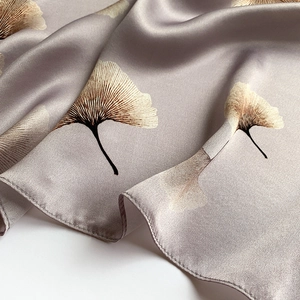 Close-up of silk square scarf featuring detailed ginkgo leaf print and satin texture