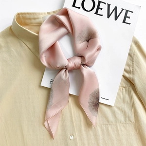 Pink silk square scarf with dark ginkgo leaf print tied on a beige shirt collar