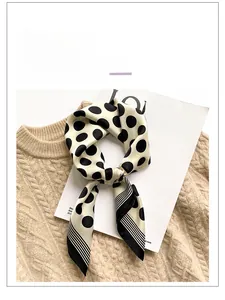 Detail of silk scarf with black polka dots and stripes over a beige knit sweater background