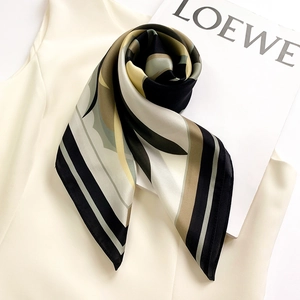 Dettaglio dei motivi geometrici sul foulard di seta con lucentezza satinata e morbido drappeggio