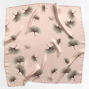 Close-up of pink silk scarf with delicate ginkgo leaf pattern and elegant satin finish