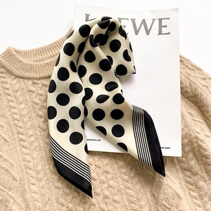 Close-up of beige silk scarf with black polka dots draped over a knit sweater