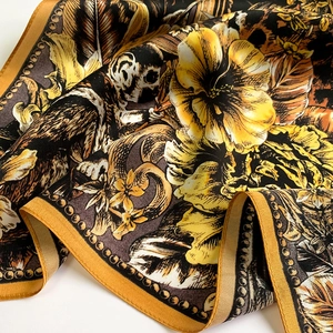 Dettaglio di un foulard in seta con stampe di lemuri e fiori e bordi arrotolati