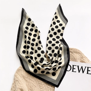 Detail of silk square scarf with classic black and white polka dots on beige knit sweater