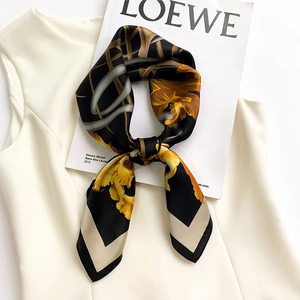 Foulard quadrato in seta con fiori gialli su fondo nero, abbinato a una rivista trendy