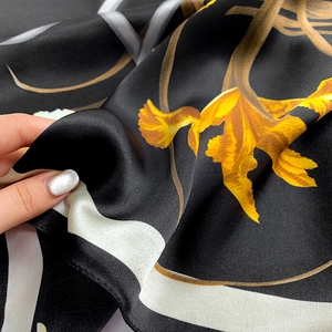 Macro di un foulard in seta che mostra la consistenza satinata e stampe floreali