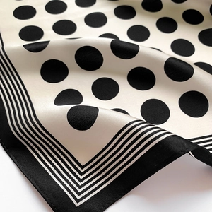 Detailed view of polka dot silk scarf featuring smooth texture and rolled edges