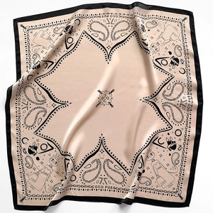 Detailed view of champagne silk scarf featuring cat illustrations and paisley patterns