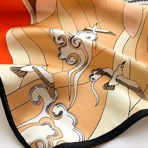 Detail of silk square scarf showing crane and sunset print with premium satin texture