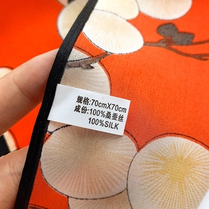Macro shot of 100% silk square scarf label showing 70x70cm size and premium fabric