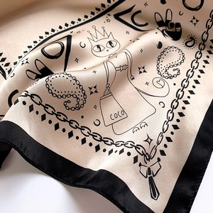 Detailed close-up of champagne silk scarf with houndstooth and cartoon cat illustrations