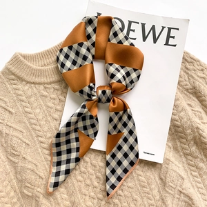 Fashionable houndstooth silk scarf in orange and black-white check on a cozy knit sweater