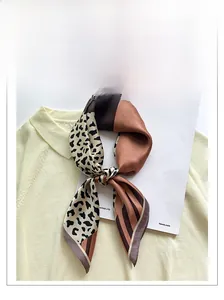 Detail of silk leopard print square scarf folded on a chic sweater and fashion magazine