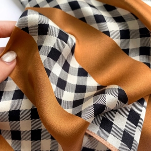Detail of silk scarf with orange and houndstooth pattern showing soft texture and sheen