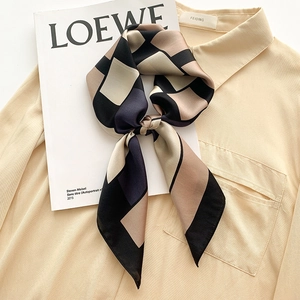 Plaid geometric pattern silk scarf in black and beige, folded on a magazine background