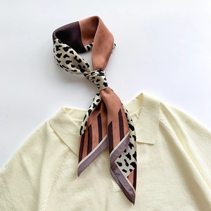 Leopard print twilly silk scarf tied on a beige knitted sweater collar for women