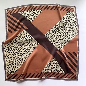 Detailed view of leopard print silk scarf with geometric patterns and satin texture