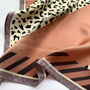 Macro shot of silk scarf showing leopard print patterns and smooth satin fabric texture