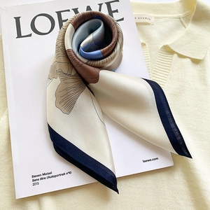 Foulard en soie à imprimé floral crème et bordures bleu marine sur magazine de mode
