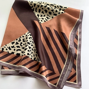 Detailed view of luxury silk scarf with geometric color blocks and leopard pattern