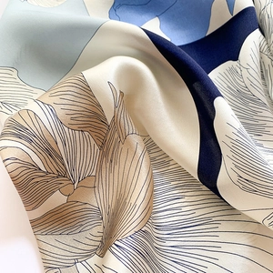 Gros plan d'un foulard en soie imprimé montrant les motifs floraux et le drapé