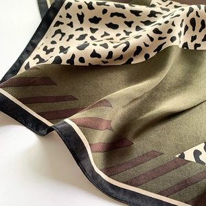 Detail of silk scarf with leopard print, olive green patterns, and satin edge finish