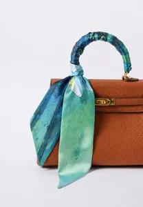 Dettaglio di un foulard in seta con stampa acquerello blu annodato al manico di borsa
