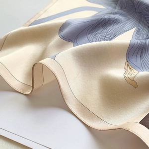 Détail d'un foulard en soie montrant une texture satinée et un motif floral bleu