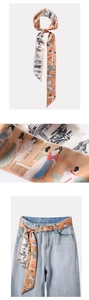 Dettaglio di un foulard twilly stampato usato come cintura su jeans con texture