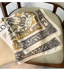 Détail d'un foulard en soie avec imprimé ours et forêt sur une chaise en cuir beige