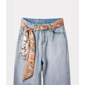 Jeans azzurri a vita alta con una cintura in sciarpa di seta colorata annodata di lato