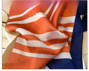 Close-up of fine overlock stitching on orange striped silk scarf highlighting premium quality