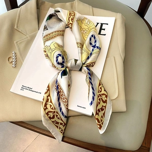 Foulard en soie motif baroque posé sur un magazine avec un blazer kaki élégant