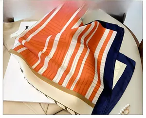 Detail of silk-like striped scarf in orange and navy draped over a fashion magazine