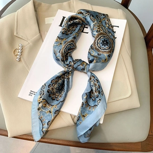Élégant foulard en soie bleue avec motif cachemire posé sur un blazer et des perles