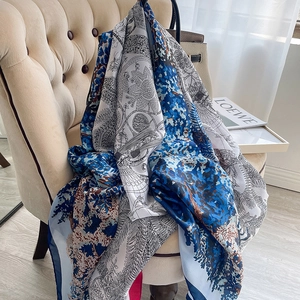 Grand foulard en soie imprimé floral bleu marine et blanc drapé sur une chaise beige