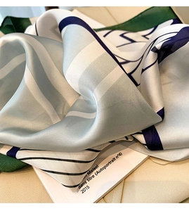 Close-up of silk-textured square scarf featuring blue and green geometric patterns
