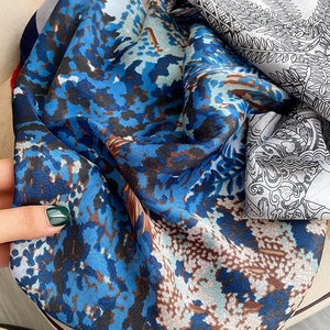 Gros plan d'un foulard en soie imprimé montrant texture abstraite et motifs botaniques