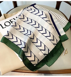 Close-up of geometric V-stripe silk scarf with dark green edges on a chair