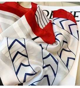 Detail of silk square scarf featuring herringbone pattern and bold red contrast edges