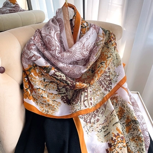 Vue détaillée d'un foulard en soie imprimé floral avec finition satinée sur canapé